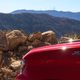 detail photo of the left front fender of a red 2023 chevy silverado zr2, with mountains in the background. the zr2 badge on the fender is visible in the foreground